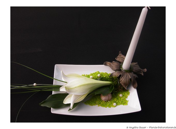 Eleganter Tischschmuck in weiß grün gehalten mit einer Lilie. Die Kerze steht in einer Blüte aus Gusseisen.